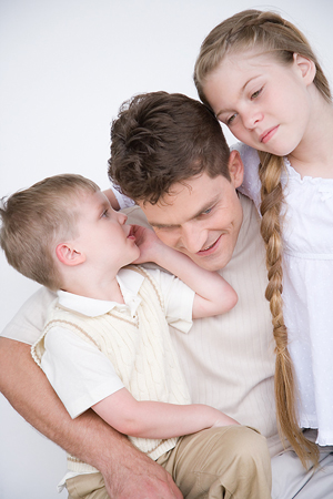 Un père avec ses enfants, le fils murmure à l'oreille du père